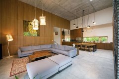 Společný obývací prostor působí díky vysokému stropu vzdušně a impozantně. Měřítko tvoří velkoformátová keramická dlažba s designem pohledového betonu a obklad stěn z dýhovaných desek