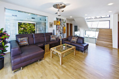 Obývací pokoj má podobu otevřené haly propojené se schodištěm, kuchyní i s bazénem. Prosklenou stěnou je dokonce vidět z lehátek  u bazénu na televizi v obýváku