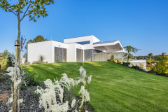 Lehce oblé linie profesionálně založené a automaticky zavlažované zahrady zjemňují střízlivou a striktně geometrickou architekturu domu