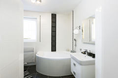 Obě koupelny jsou vybaveny rohovou vanou i sprchou. Bílý obklad je nadčasový a opticky prosvětluje a zvětšuje prostor