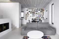 Také interiér je velmi střízlivý, bílé omítky a šedý pohledový beton architekti doplnili na míru navrženým nábytkem  z bílých MDF desek. Barevnost sem vnášejí jen hřbety knih a drobné doplňky