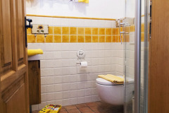Koupelna Žlutého pokoje s terakotovými dlaždicemi na podlaze a pruhem v „barvě pokoje“. Garnýž a klika je dílem místního kováře, který takto vybavil celý dům