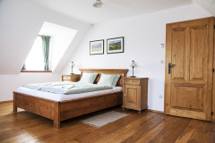 Útulný podkrovní pokoj je zařízen prostě, s důrazem na přírodní materiály a v přirozené barvě dřeva. Tomu odpovídají také dřevěné podlahy z masivu